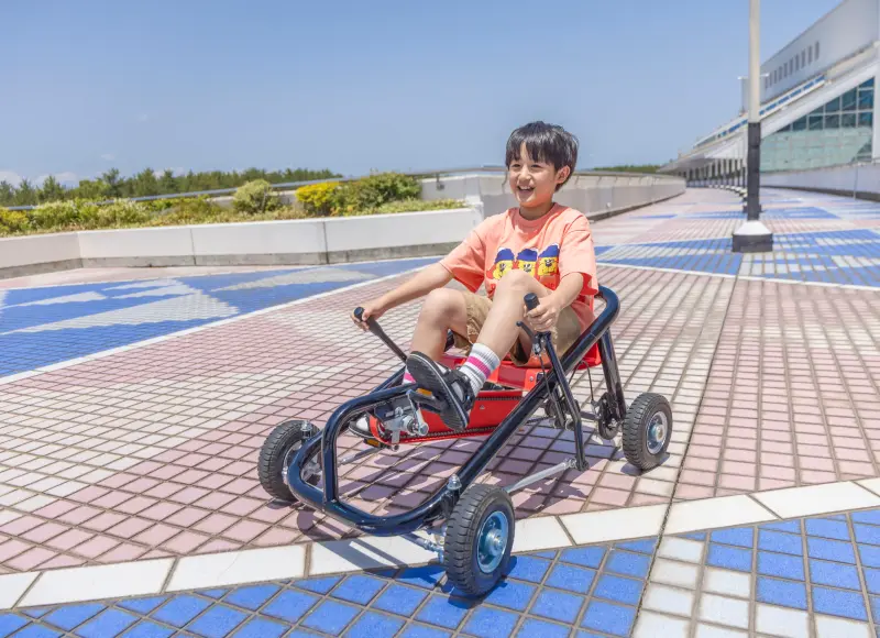 屋外でペダルゴーカートを楽しむ子ども